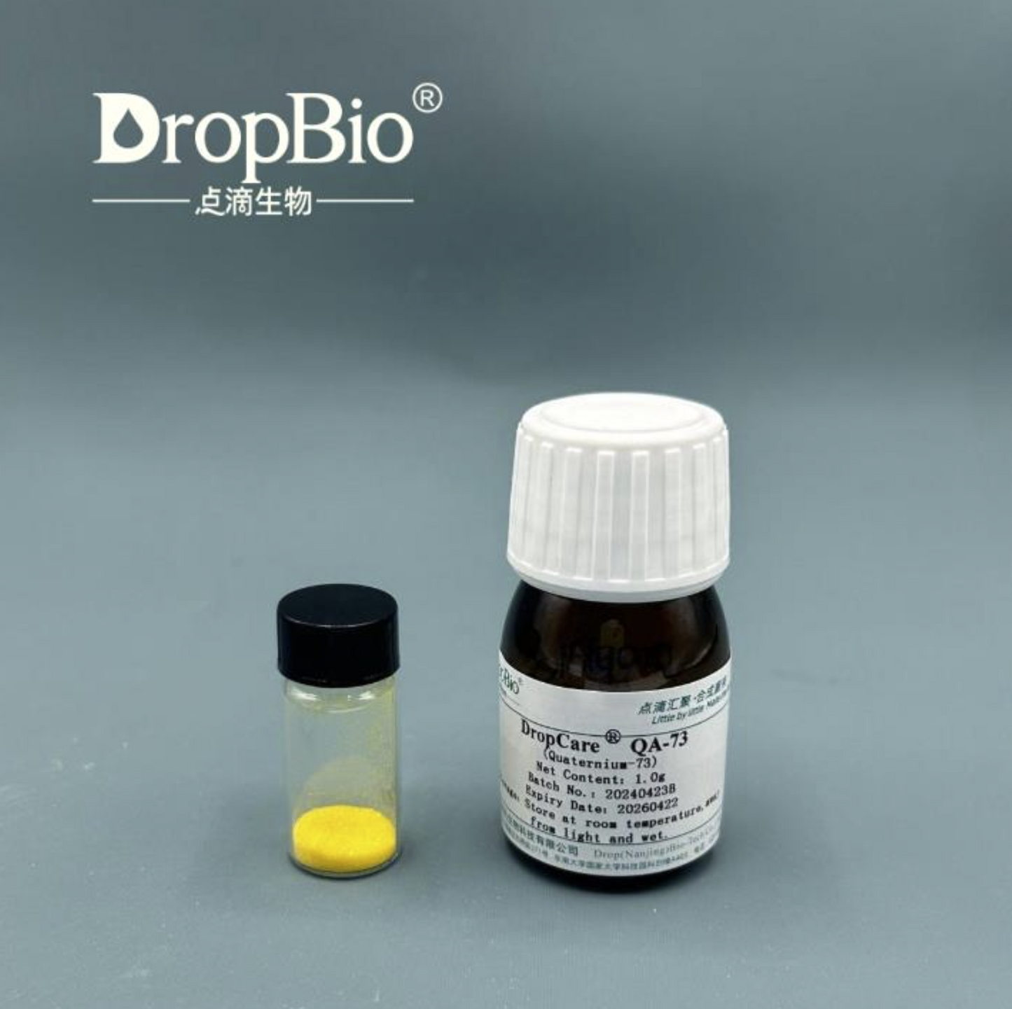 Two small bottles with labels on a gray background, featuring the DropBio Quarternium-73 Powder brand.