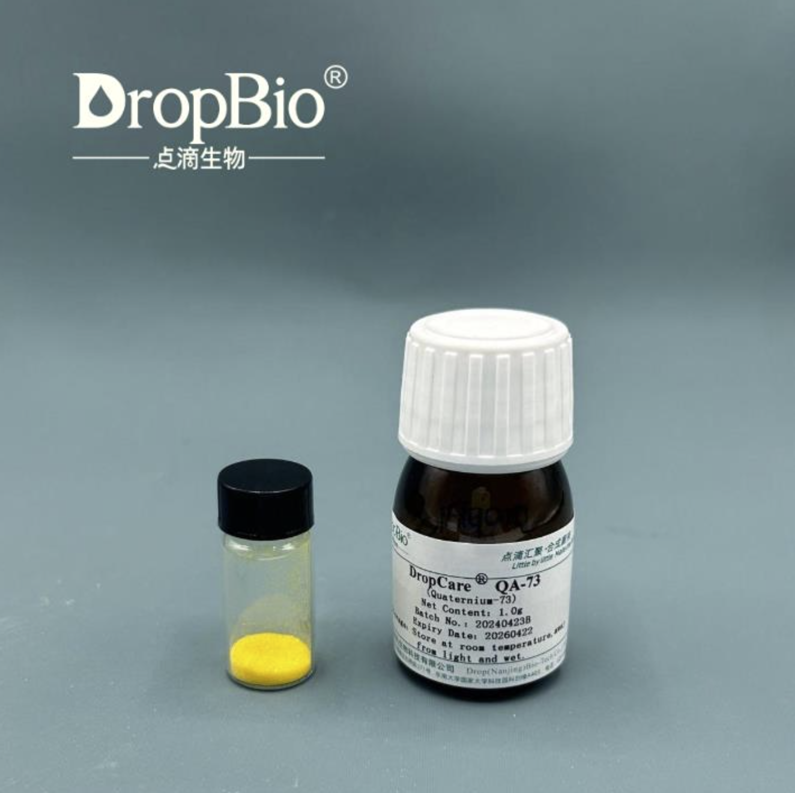 Two small bottles with labels on a gray background, featuring the DropBio Quarternium-73 Powder brand.